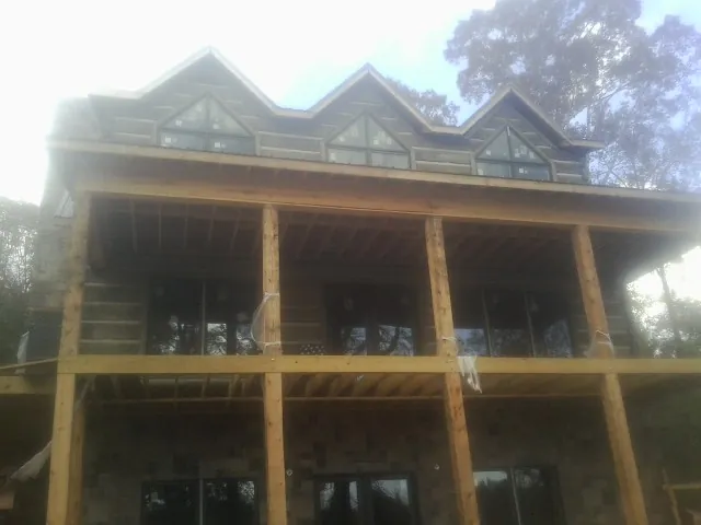 Dormers and porch framing on a large log home under construction — Roof Coating work by our crew in Southampton